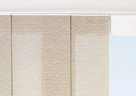 Panel track blinds made of Chilewich Bamboo in Chalk are installed in an outside mount on a white track over a tall window
