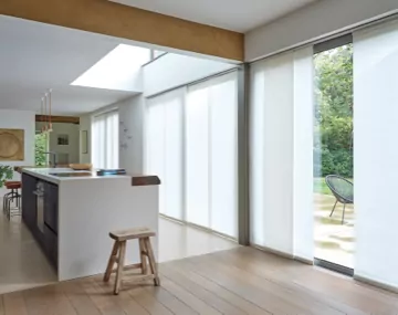 Panel Track Vertical Blinds hung over large patio doors in an open kitchen with a large white centered island