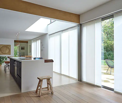 Panel track blinds made of Park in Winter cover wall-to-wall windows and sliding glass doors in a mid-century modern kitchen