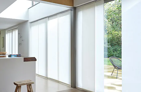 Vertical Blinds made of Park in Winter cover wide windows in a large modern space with a kitchen island and a stool