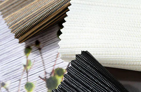 Swatches for panel track blinds feature natural textures and are displayed decoratively with leafy twigs