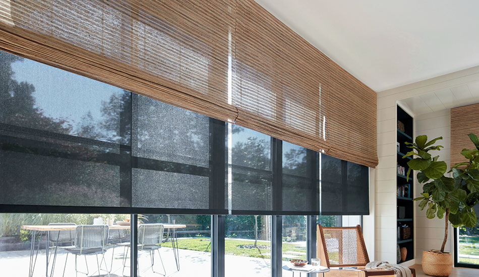 A room with tall windows has woven shades made of Artisan Weaves Cove in Beige over Solar Shades made of 5% in Black
