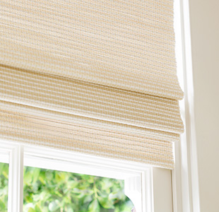 A close-up of a Woven Wood Shade made of Somerset in Cloud with privacy lining shows some light filtering through