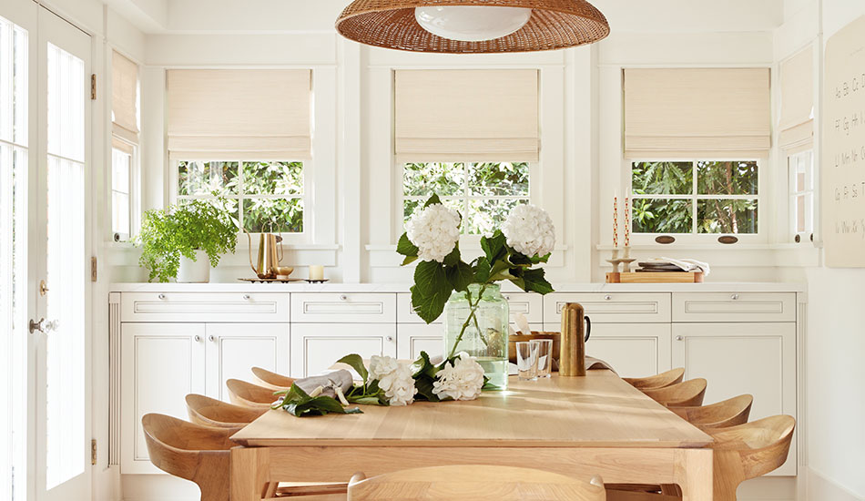 A beautiful boho inspired dining room has woven shades made of Artisan Weaves Somerset in Cloud to add more texture