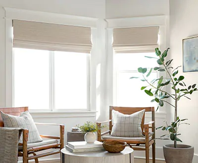 Window treatments for bay windows include Waterfall Woven Wood Shades made of Bayshore in Parchment in a sitting room