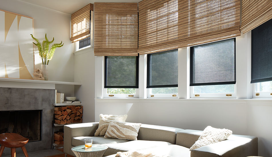 A bright family room features woven shades made of Artisan Weaves Cove in Beige layered with Solar Shades of 3% in Black