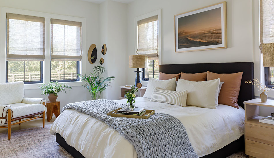 Window coverings in a boho-inspired bedroom include Waterfall Woven Wood Shades made of Grassweave in Hemp