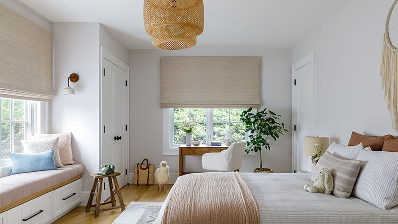 A boho-inspired bedroom features Waterfall Woven Wood Shades made of Grassweave in Hemp for inviting organic texture