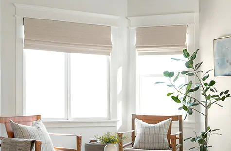 Woven wood shades made of Bayshore in Parchment adorn a bay window in a sitting area in place of bay window curtains