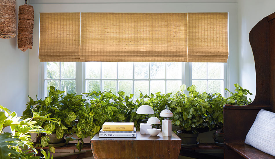 Modern shades with a woven wood design in an inviting sunroom include golden toned waterfall woven wood shades made with natural fibers