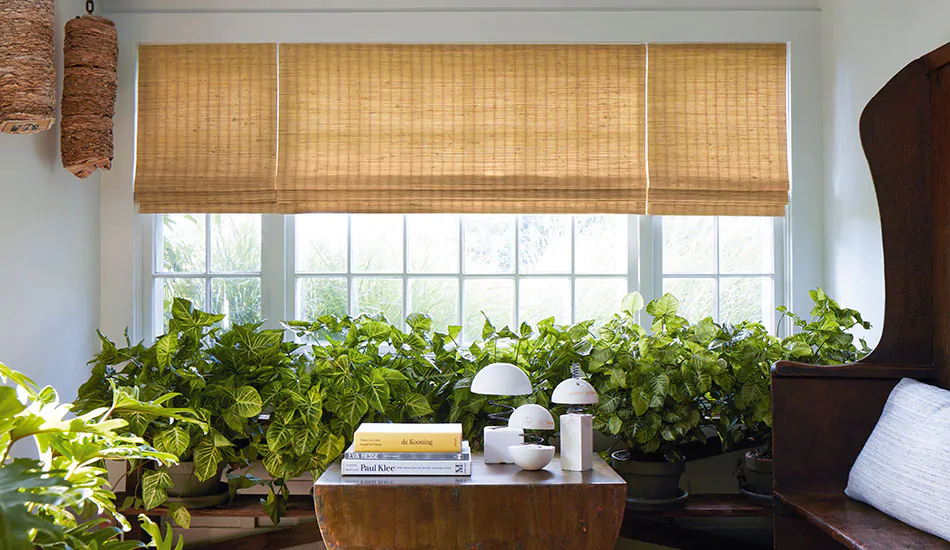 Modern window treatments in an inviting sunroom include golden toned waterfall woven wood shades made with natural fibers