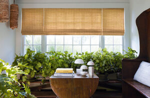 Window shades in an inviting sunroom include Waterfall Woven Wood Shades made of Coastline in Oat for a warm golden color