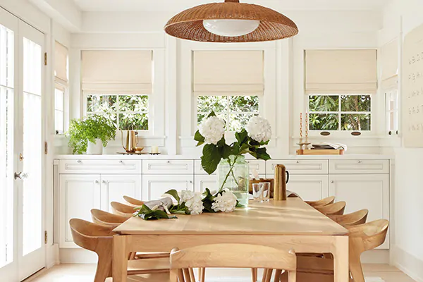 A bright dining room with a modern wood dining set has woven wood shades made from Somerset material in Cloud