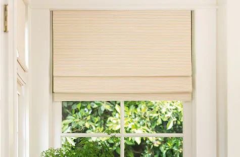 A window in a bright kitchen with warm off-white walls has woven window shades made from Somerset material in Cloud