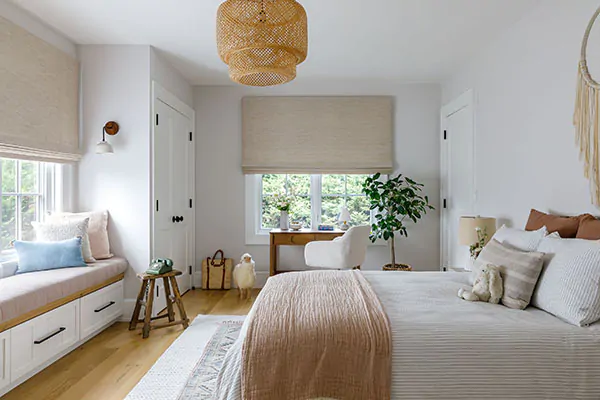 A boho-inspired bedroom features Waterfall Woven Wood Shades made of Grassweave in Hemp to complement other organic elements