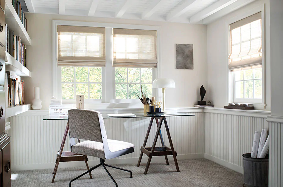Window treatment trends 2023 include neutral colors and natural textures like in this bright office space