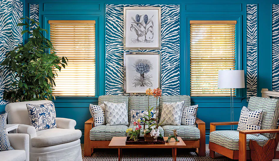 A bright turquoise-painted room has Wood Blinds made of Bamboo in Natural that bring a warm natural wood tone to the space