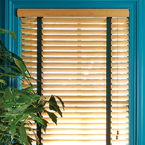A close up of Wood Blinds made of Bamboo in Natural show a light wood tone that complements the turquoise-painted walls