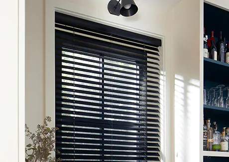Wood Blinds made of 2-inch Basic wood in Ebony are inside mounted above a wet bar with black shelving