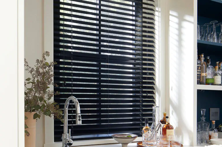 Small window blinds made of 2-inch Basic Wood in Ebony add contrast to a bright wet bar area in a kitchen