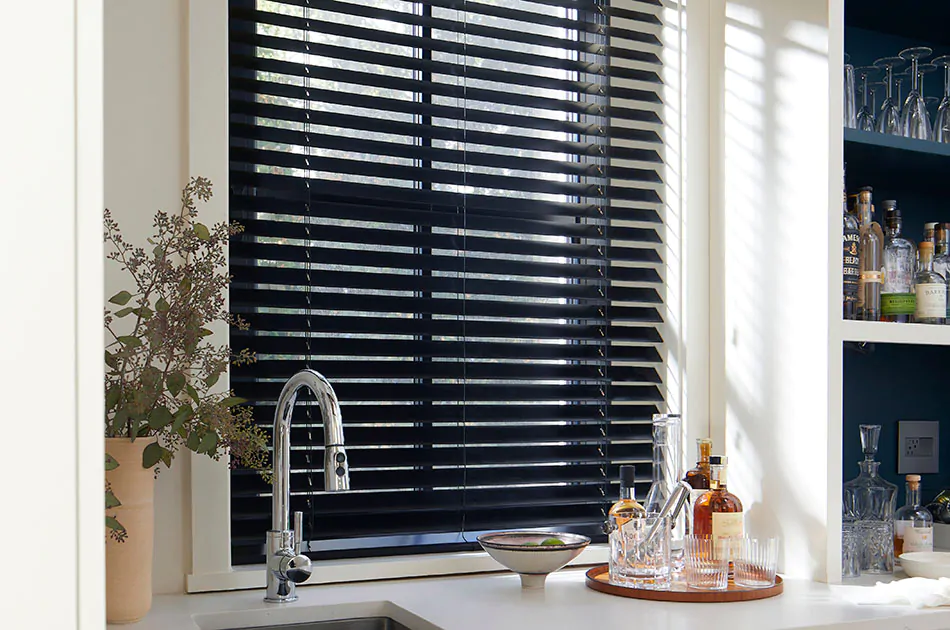 Small window blinds made of 2-inch Basic Wood in Ebony add contrast to a bright wet bar area in a kitchen