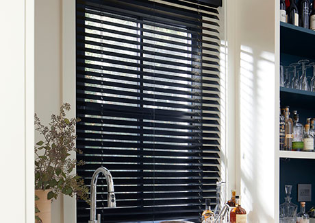 Types of blinds include Wood Blinds made of 2-inch Basic in Ebony which contrast off-white walls in a wet bar window
