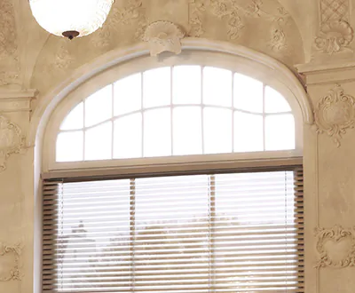 An elegant elliptical arch in a baroque style room features Wood Blinds made of 2-inch Exotic in White Oak below the arch