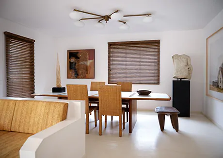 A dining room with a mid-century modern aesthetic features wood furniture and 2-Inch Exotic Wood Blinds in Zebrano