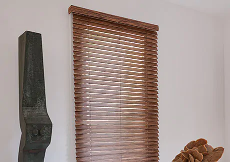 Wood Blinds made of 2-inch Exotic wood in Zebrano are outside-mounted on a tall window in a dining room with eccentric decor
