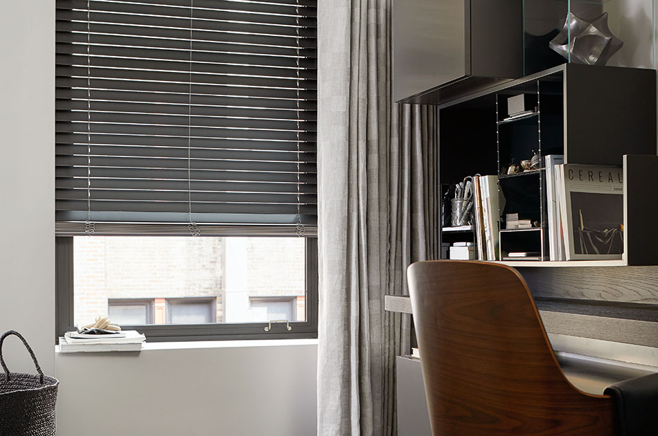 Office with wood blinds on a tall window, highlighting types of window shades and blinds with durable slat design and adjustable light control