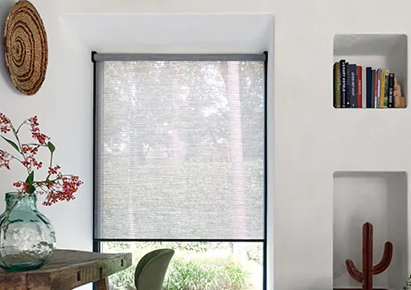 A Woven Roller Shade made from Jackson in Grey is used as sunroom window treatments covering a tall window in a small space