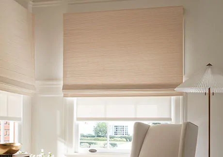 A warm inviting room features a Waterfall Woven Wood Shade made of Somerset in Cloud in an outside-mount application