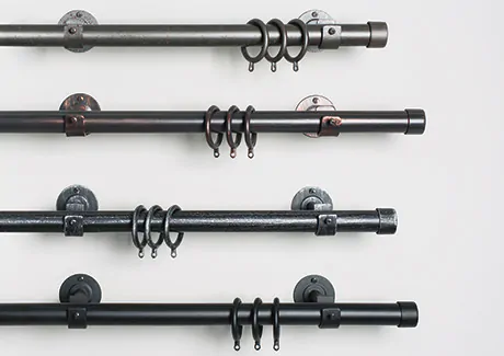 Close-up of four wrought iron drapery hardware sets made up of rods and rings stacked one on top of the other