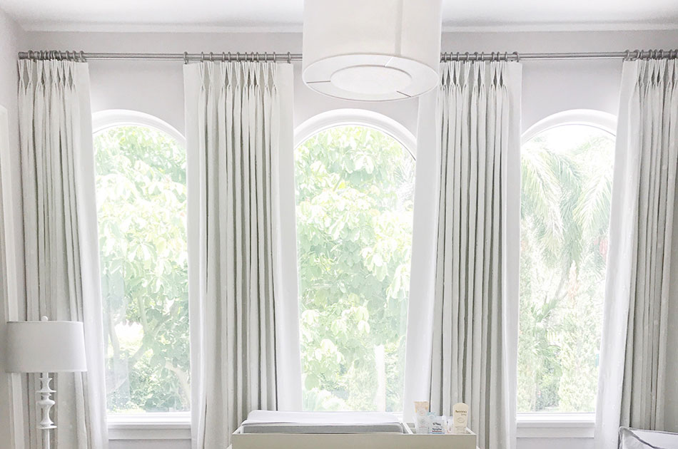 Light-filled room with curtains for arch windows and soft white drapery panels”